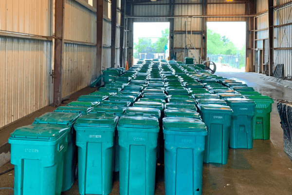 Clean green trash bins organized inside a commercial cleaning facility