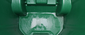 Green trash bin interior after cleaning with visible water rinse and sanitized surface