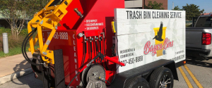 A red and yellow Bayou Bins cleaning service trailer attached to a pickup truck on a sunny day.