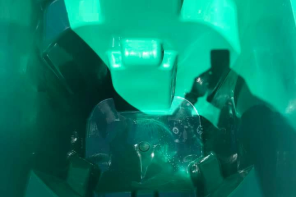 A close-up, top-down view inside a bright green plastic container with a clear, bubbly liquid at the bottom.