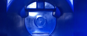 A top-down view of the dirty, muddy bottom of a blue container or vat with some white debris.