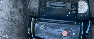 A close-up, top-down view inside a dirty, empty green plastic trash can with some debris at the bottom.