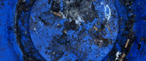 A close-up of a vibrant blue surface covered in numerous small, light-colored particles, likely water droplets and debris.