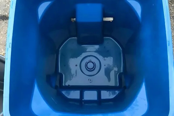Inside view of an empty, clean blue recycling bin with a drain at the bottom.
