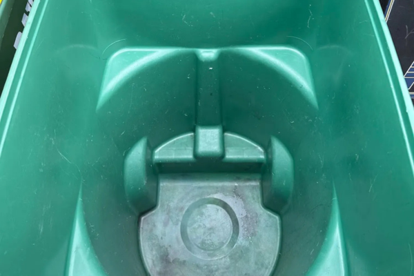 The interior of an empty, deep green plastic storage bin with textured bottom and side reinforcement.